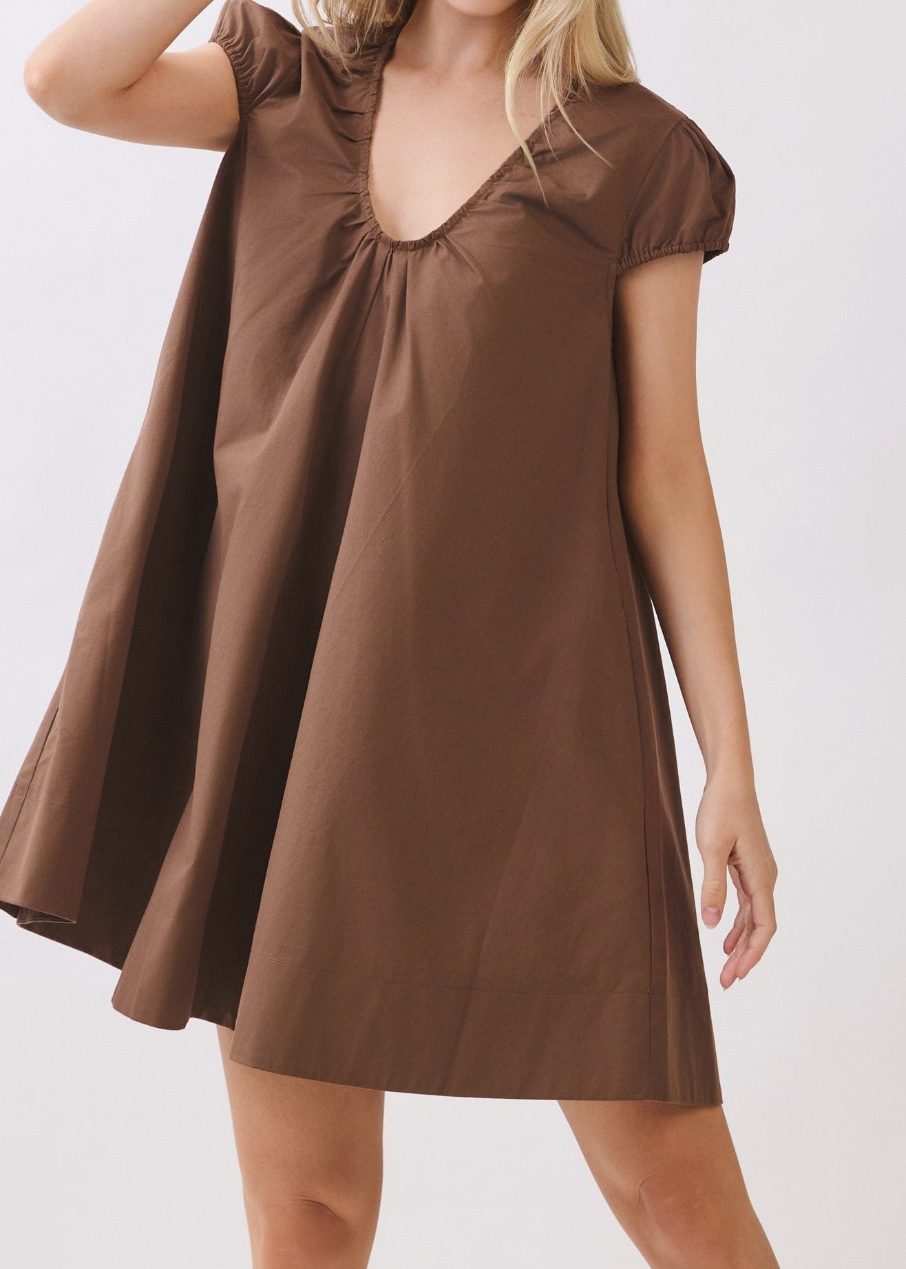Soak up the southern charm in our Sweet Escape Swing Dress, crafted from soft brown cotton for an effortlessly breezy feel. This mini dress features a flattering deep V-neck, easygoing short sleeves, and a playful swing silhouette that drapes just right. Elle Boutique, Zachary, LA.