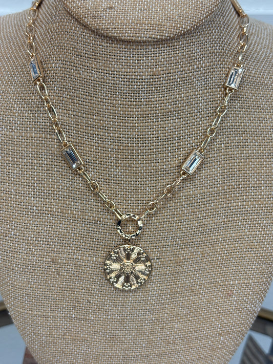 Shimmery gold necklace with crystal accents and retro medallion on chunky links—perfect for layering. Elle Boutique, Zachary, LA.
