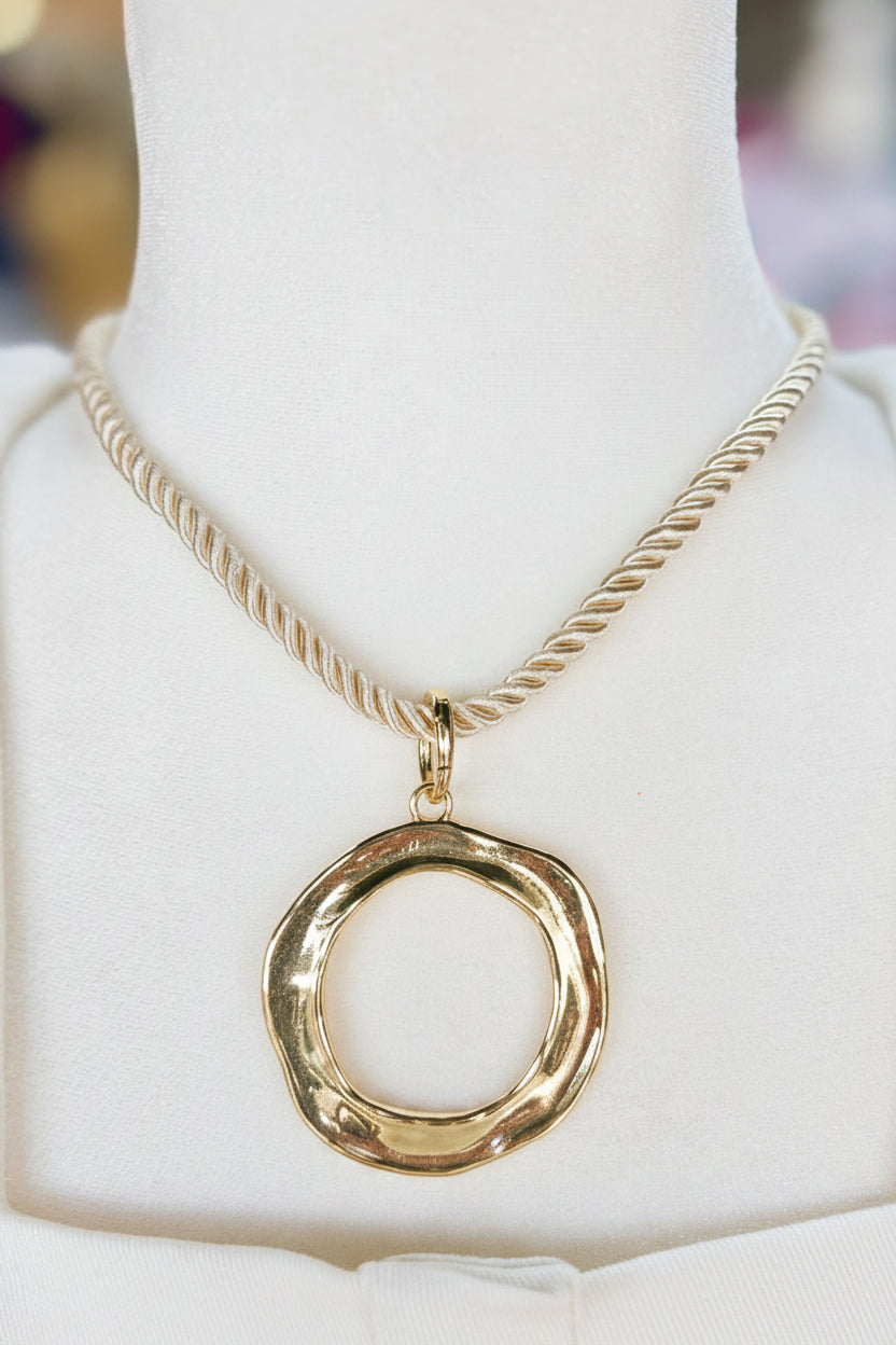The High Tide Rope Pendant Necklace has a gold hammered medallion on a twisted chainâcharming coastal vibes. Elle Boutique, Zachary, LA.