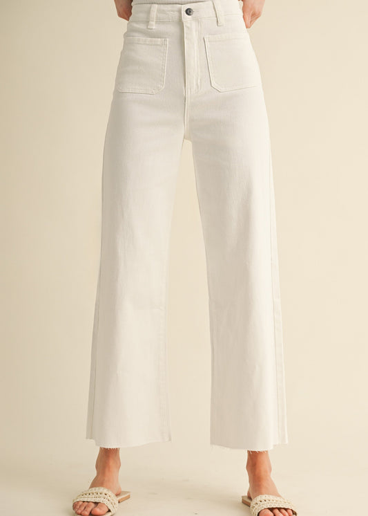 Charming white cotton wide-leg jeans with patch pockets, frayed hems, and woven sandals. Elle Boutique, Zachary, LA.