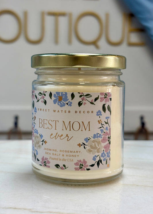 Sweet floral candle in a glass jar with gold lid, jasmine & honey notes—perfect for Mom. Boutique sign peeks behind. Elle Boutique, Zachary, LA.