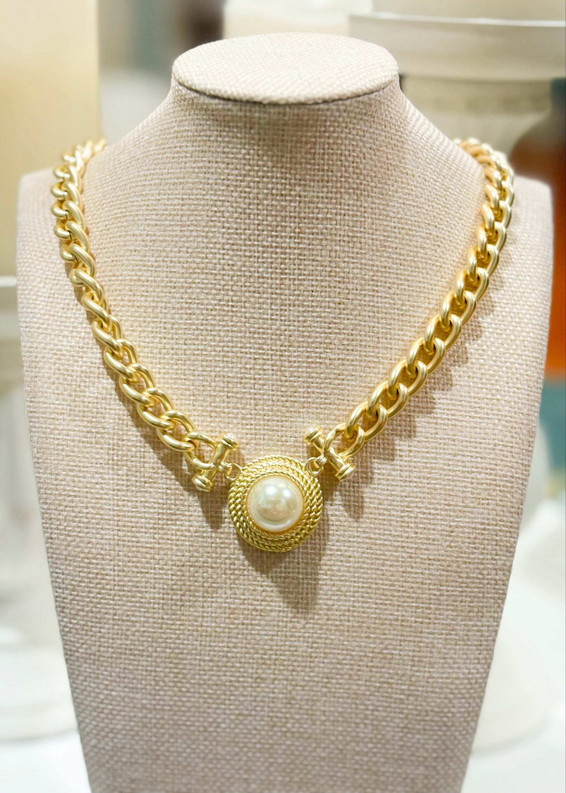 A darling gold chain necklace with a round textured pendant and white pearl, perfect for layering. Elle Boutique, Zachary, LA.