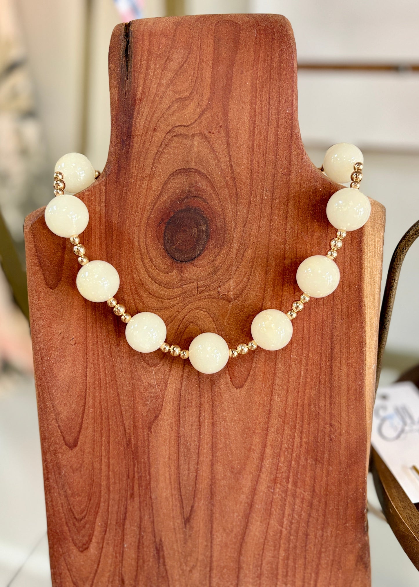 The Champagne & Pearls Necklace shines with creamy ivory beads and gold accents, displayed sweetly at Elle Boutique, Zachary, LA.