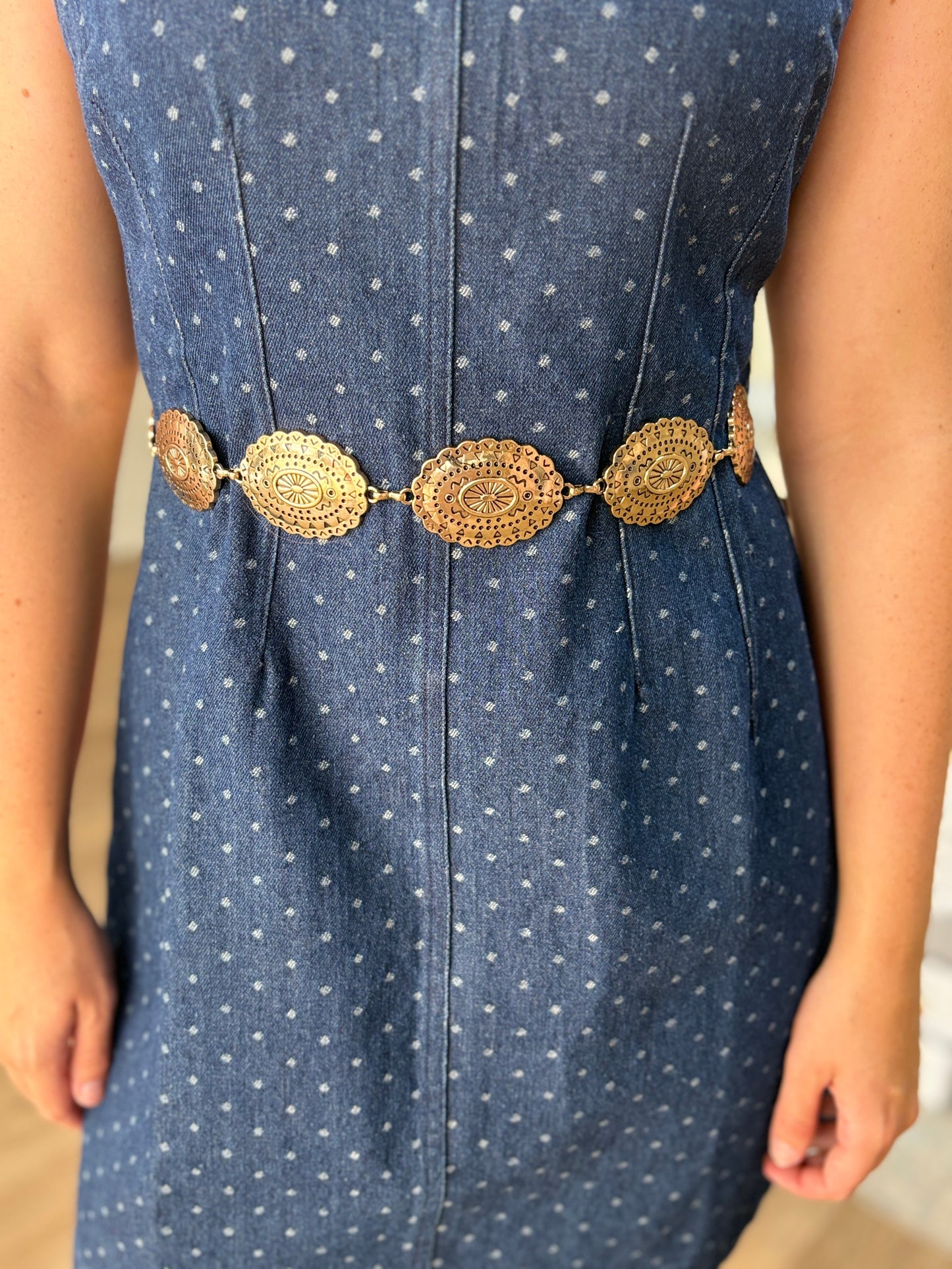 A gal twirls in a breezy blue polka dot dress, gold medallion belt at the waist, adding Western flair. Elle Boutique, Zachary, LA.