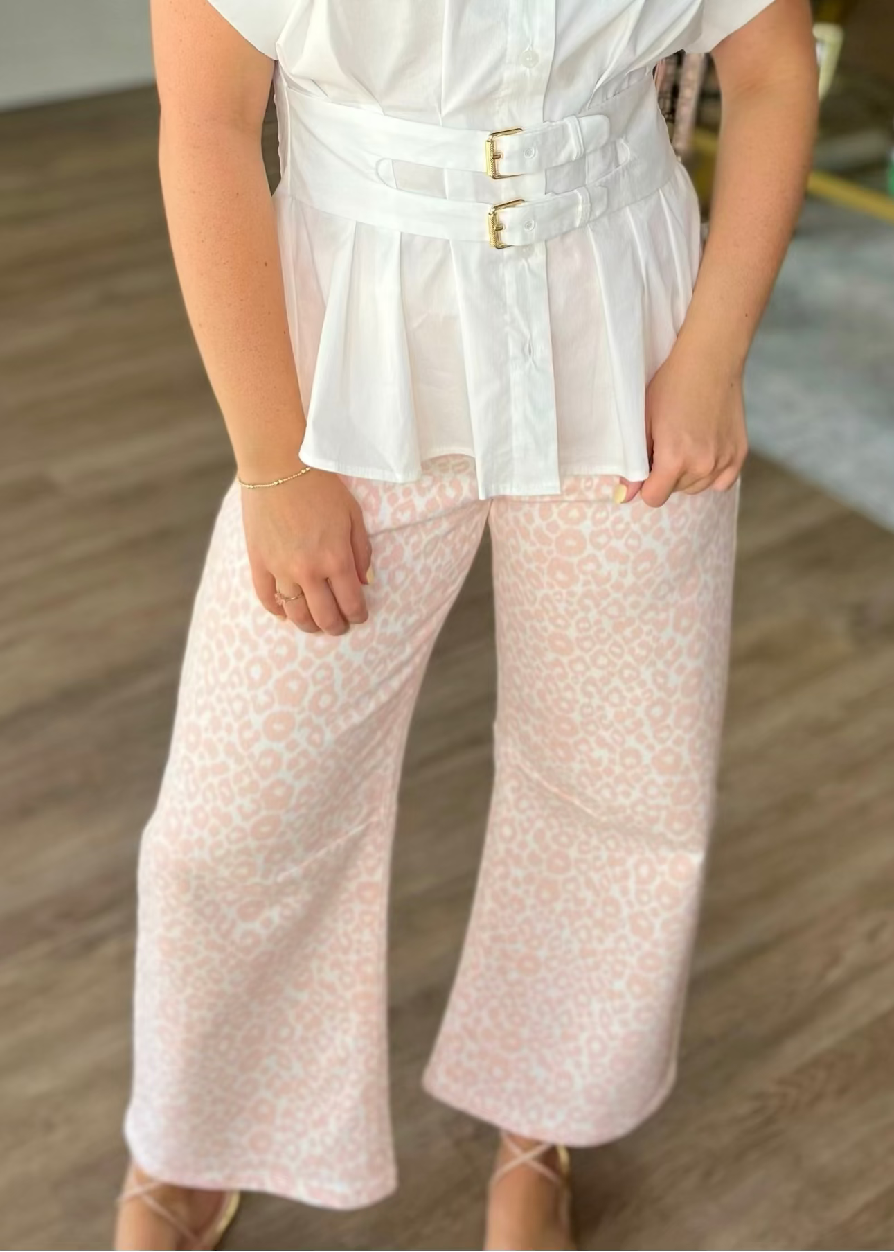 A lady shows off soft cotton Pink Leopard Barrel Leg Jeans, high-rise fit, paired with a belted white blouse. Elle Boutique, Zachary, LA.