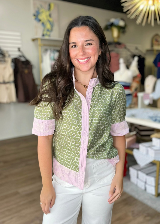 A smiling woman in a flowy, cotton-blend Mandarin Mixed Print Button Down Top and white pants, shopping at Elle Boutique, Zachary, LA.