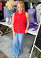 A cheerful woman wears a comfy red sleeveless button top and soft high-rise wide leg denim, in a cozy shop. Elle Boutique, Zachary, LA.