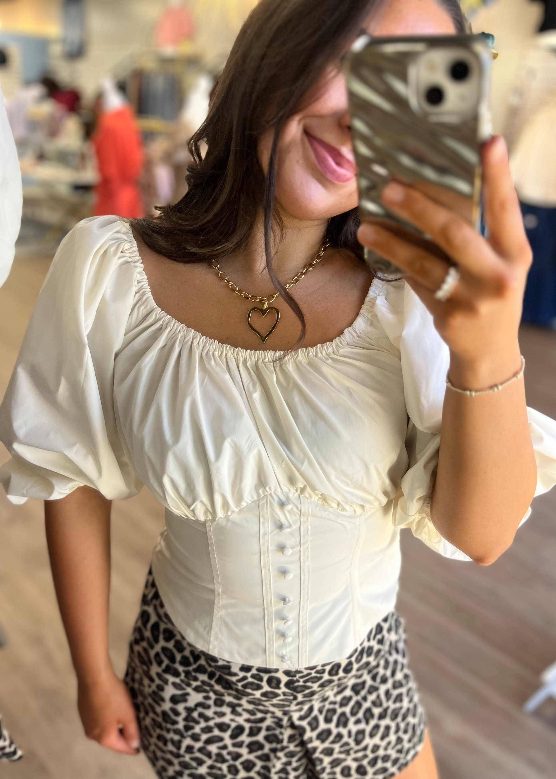 Smiling in the Jezebel cotton corset top in soft ecru, leopard shorts, and a heart necklace. Elle Boutique, Zachary, LA.